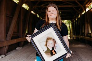 Professional photographer displays their portfolio of portrait photographs inside a rustic wooden covered bridge.