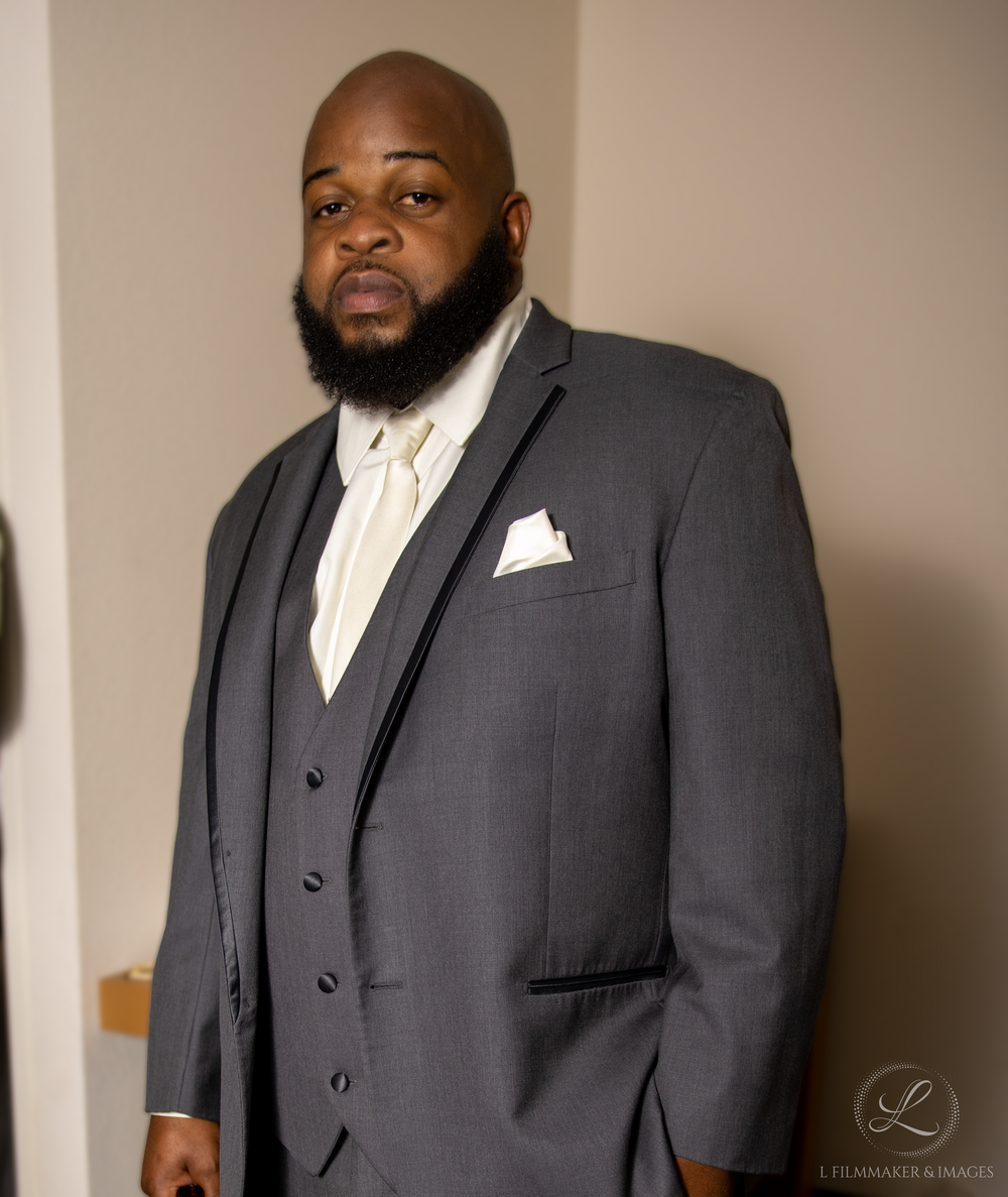 Formal portrait of groom in charcoal gray three-piece suit with white tie.
