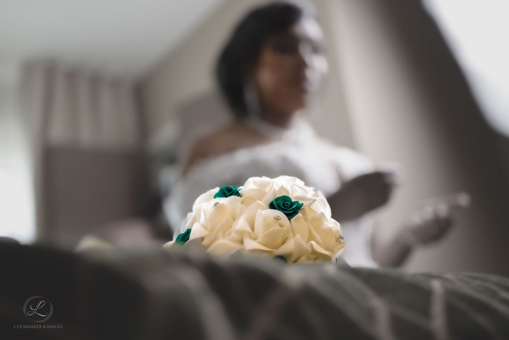Cream and teal roses in soft focus with blurred bridal silhouette in background.