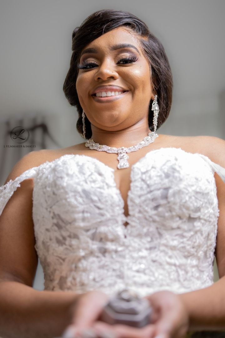Close-up portrait of a radiant bride wearing a crystal necklace and lace wedding gown.