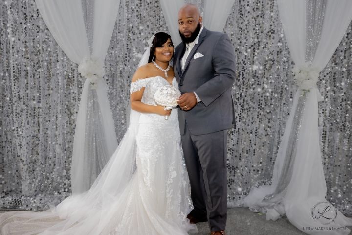 Romantic wedding portrait with sparkly silver backdrop and elegant decor.