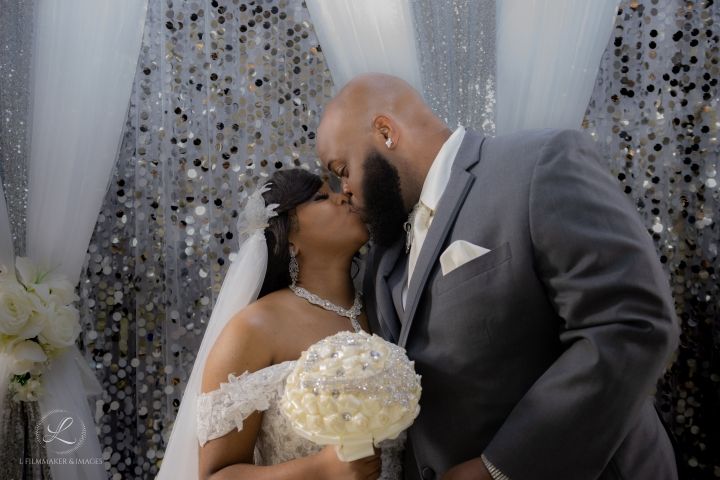 A tender wedding moment captured under a sparkly backdrop as the couple shares a romantic kiss.