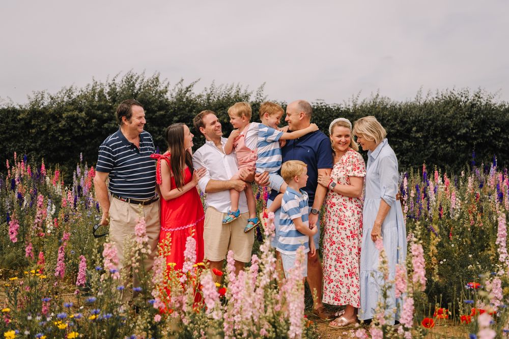 Large family gathering in a colorful wildflower garden, smiling and embracing outdoors.