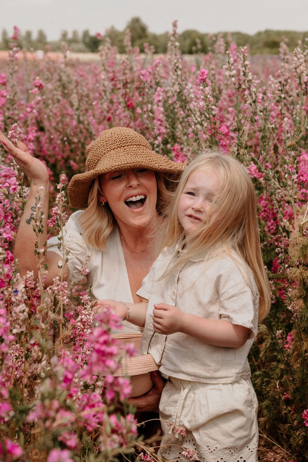 A joyful moment shared between two people surrounded by blooming pink wildflowers in a sunny field.