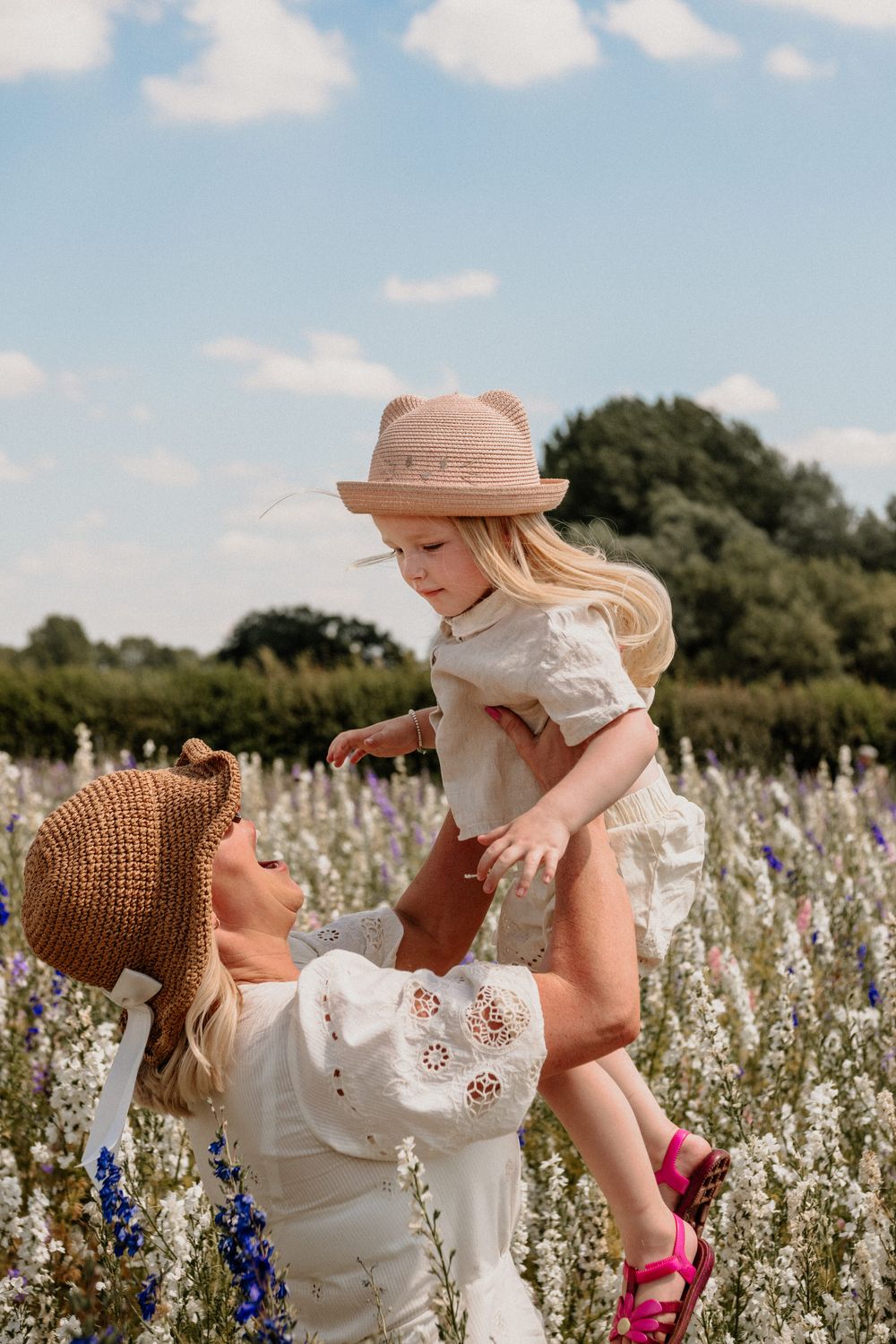 Mother and child playing together in a blooming wildflower meadow on a sunny summer day.
