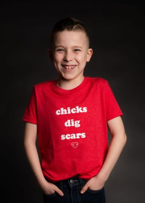 Red t-shirt with 'chicks dig scars' text against dark background.