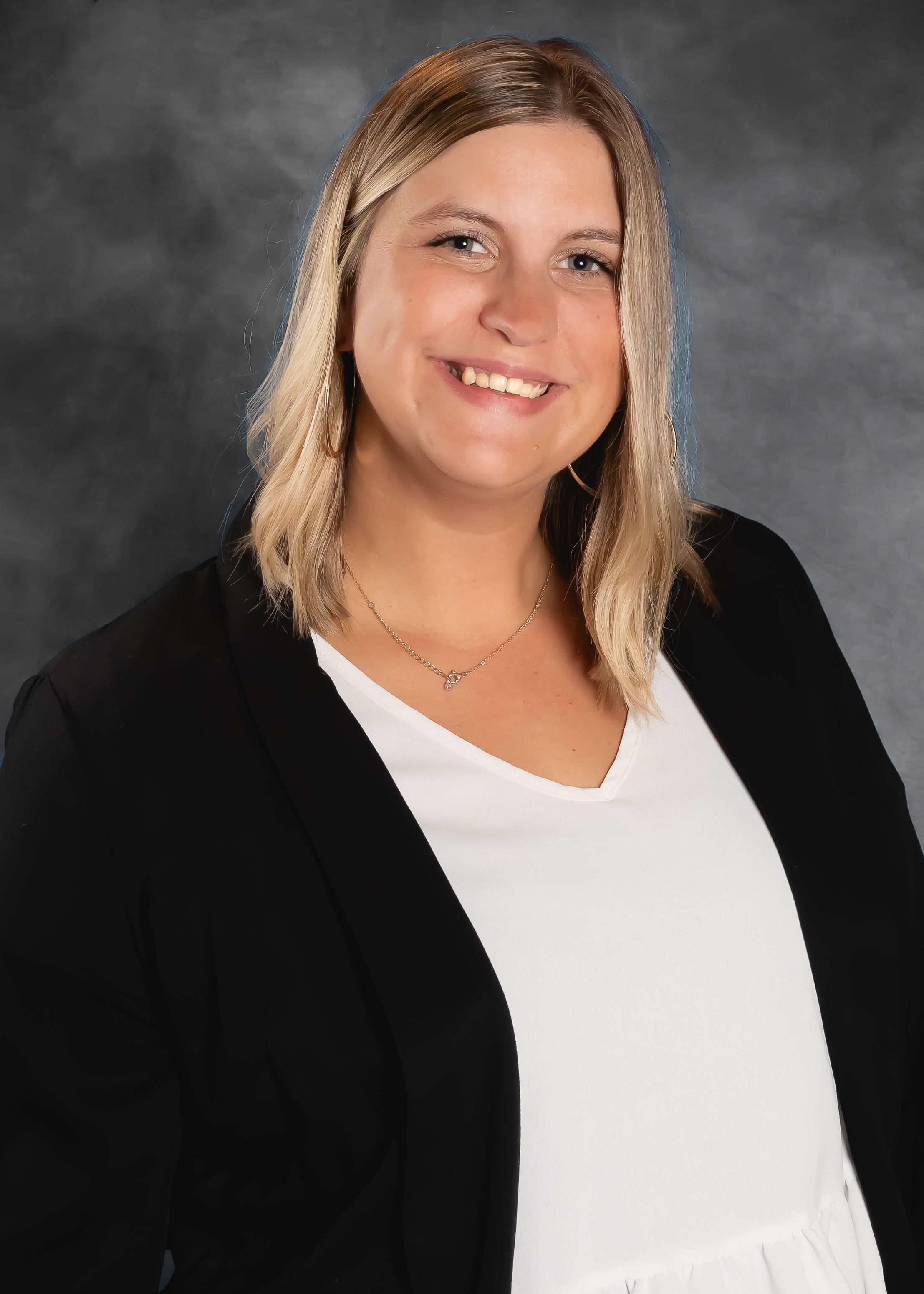 Professional headshot of woman wearing black cardigan and white top.