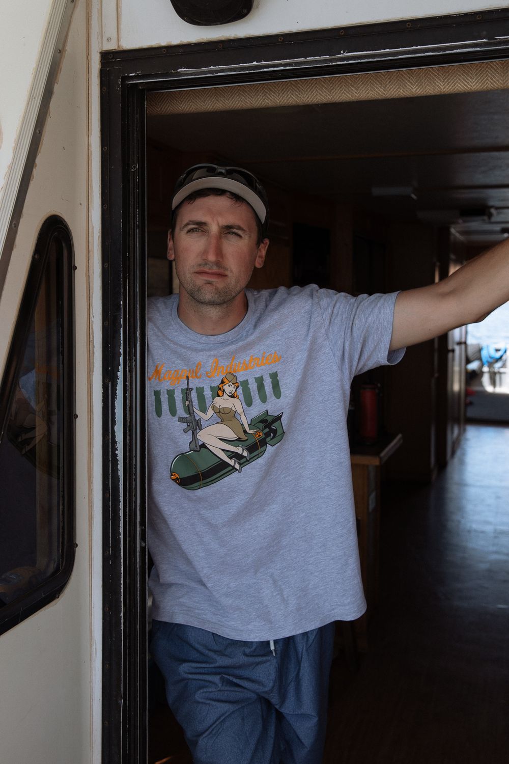 man in t-shirt standing in door opening of houseboat looking out ahead