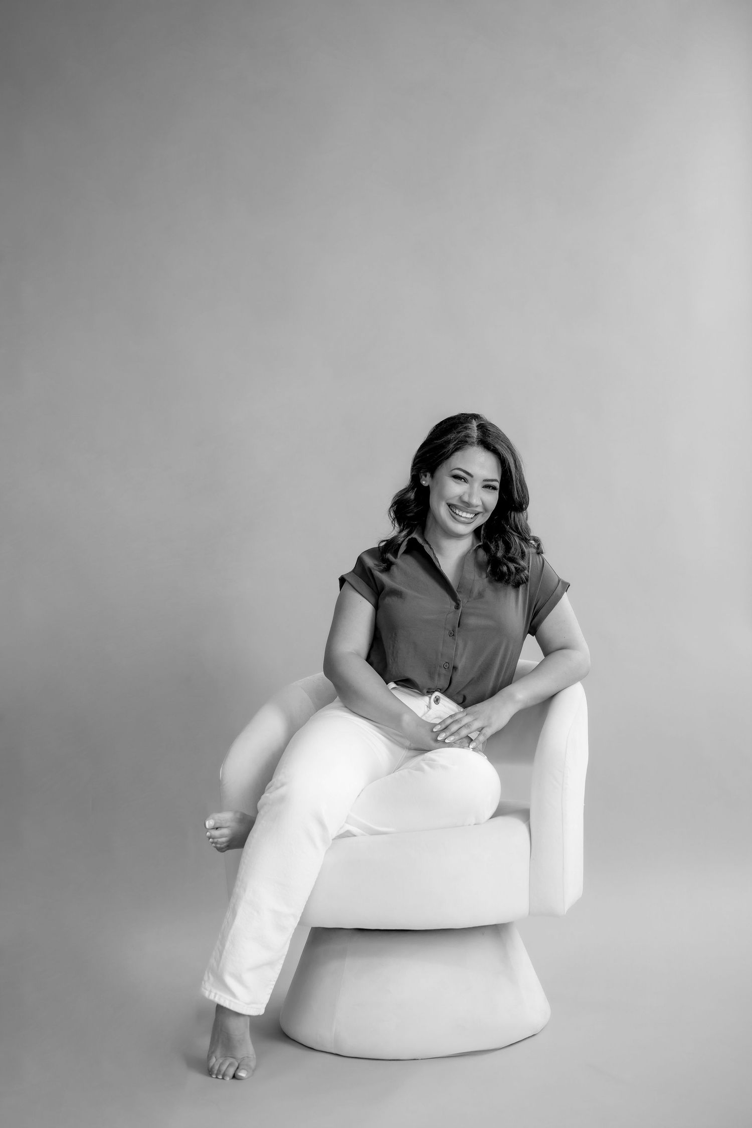 A branding photo of a real estate agent stands confidenconfidently in home office with contemporary furniture and a large clock on the wall.