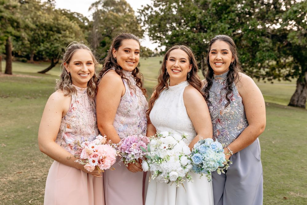 Wedding party in pastel dresses and formal attire posing together outdoors.