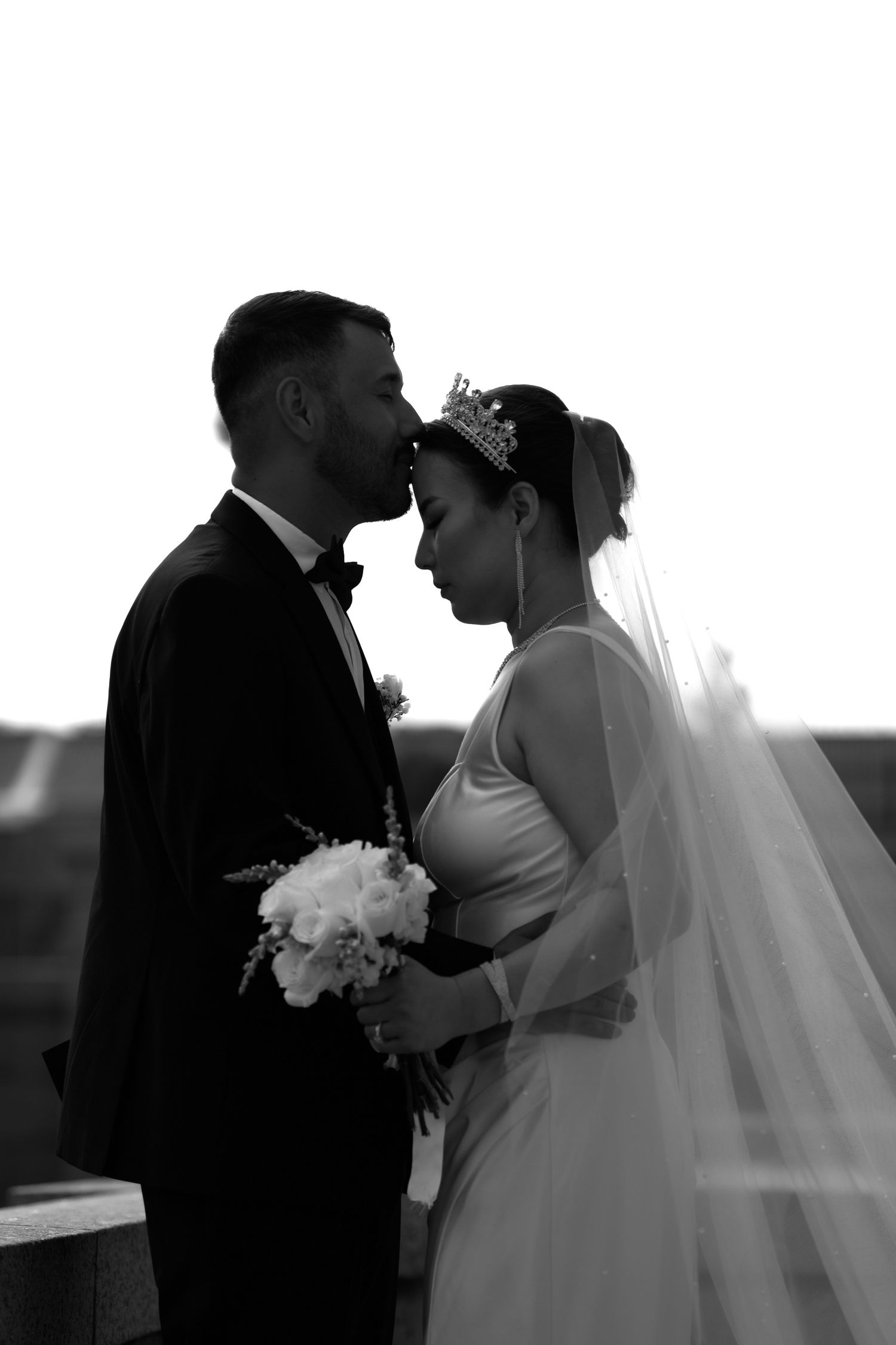 Silhouetted wedding couple shares intimate moments in black and white photography.