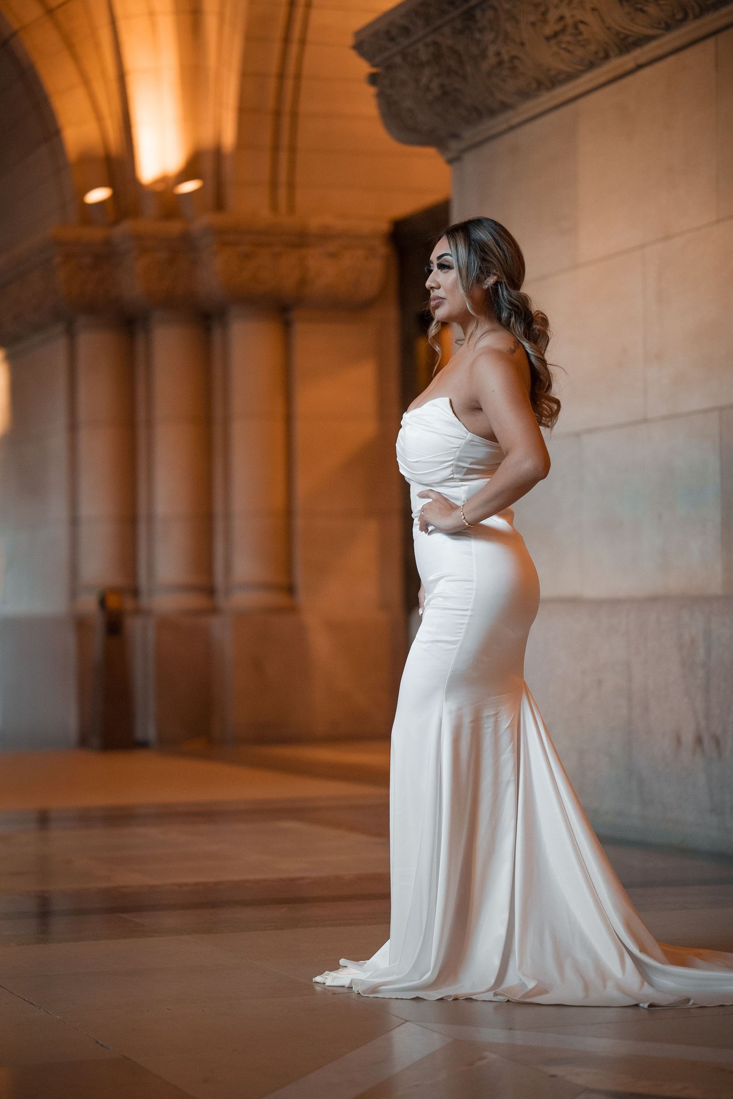 Elegant bridal portraits in a white dress against classical architecture with warm ambient lighting.