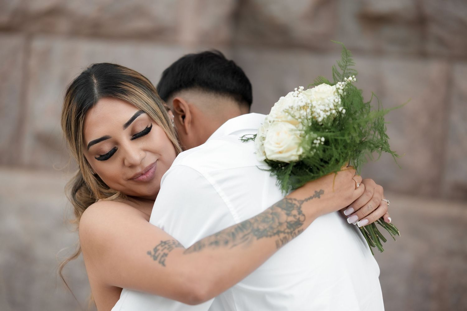 A tender embrace between newlyweds as they share an intimate moment with white roses.