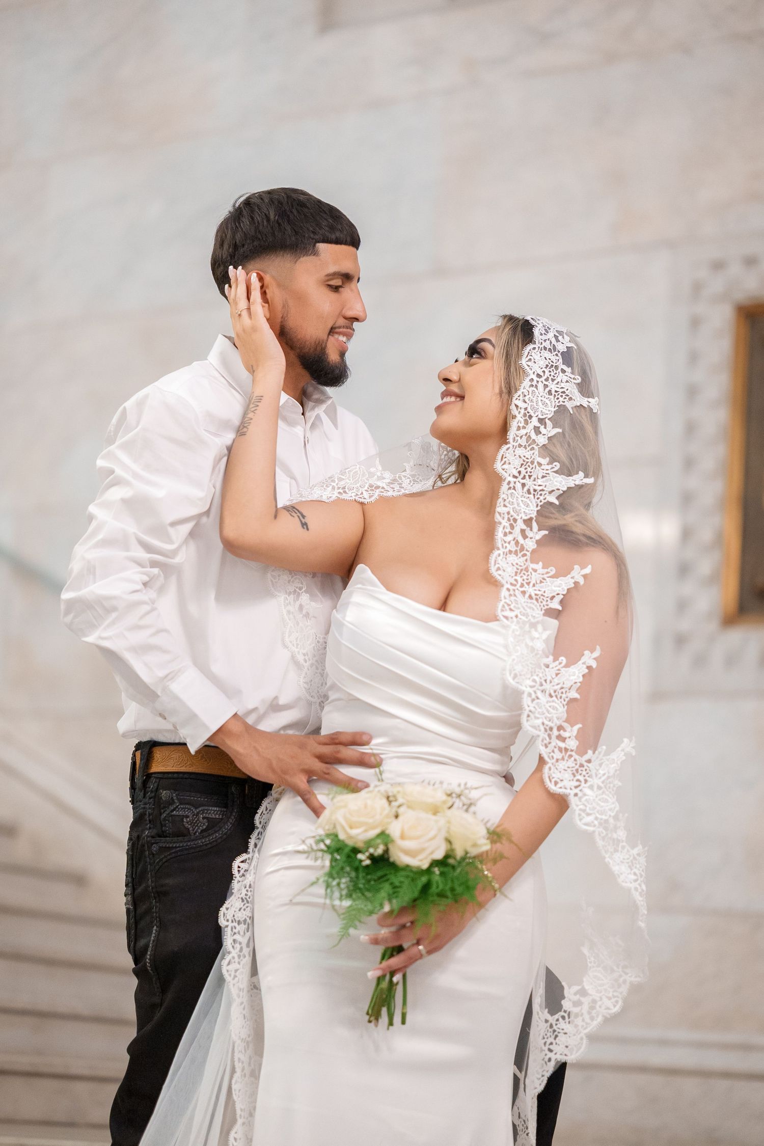 A romantic wedding moment captured as newlyweds embrace in an elegant marble venue.