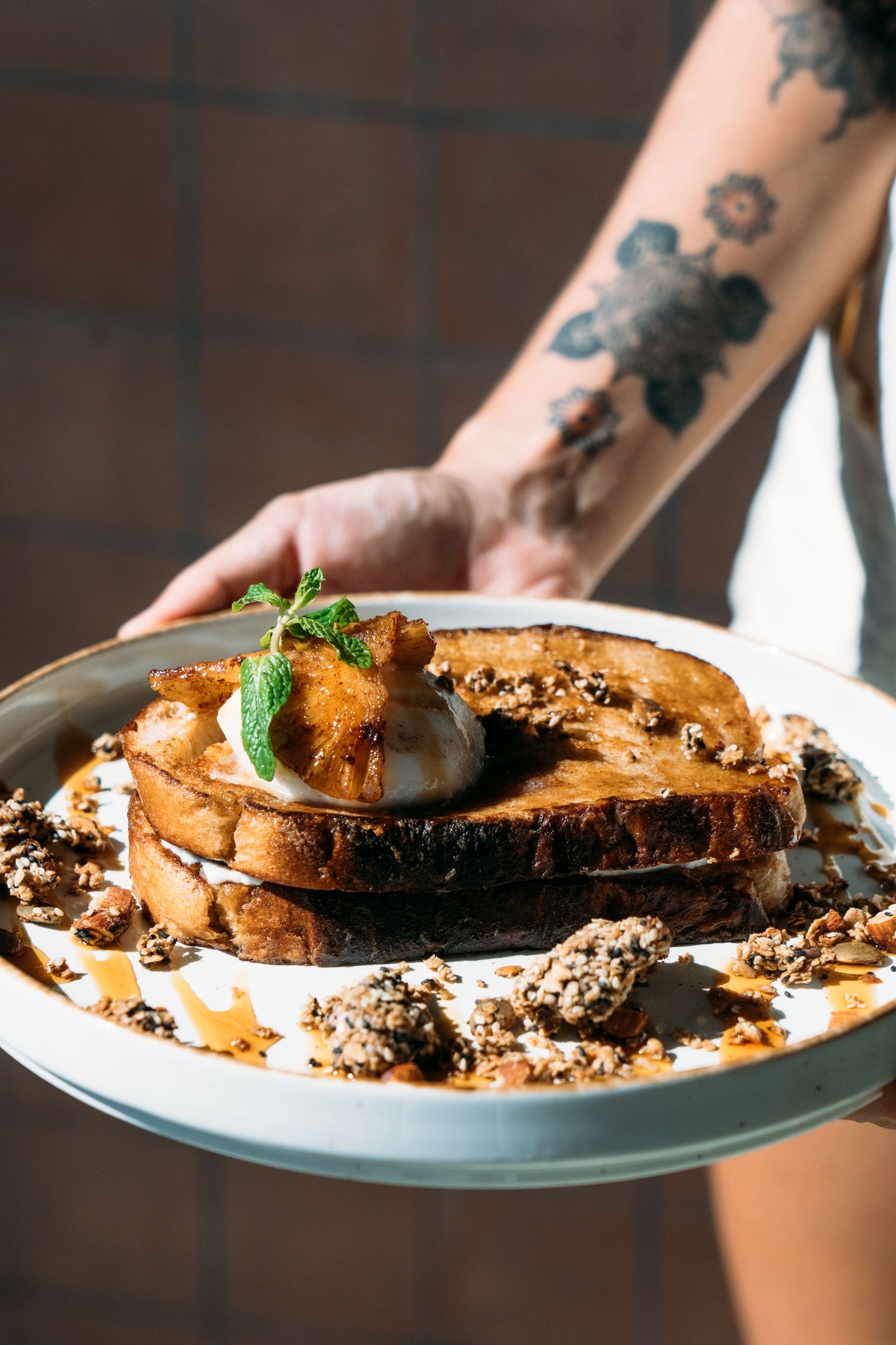 Close-up of artisanal toast with toppings and garnishes on white plates.