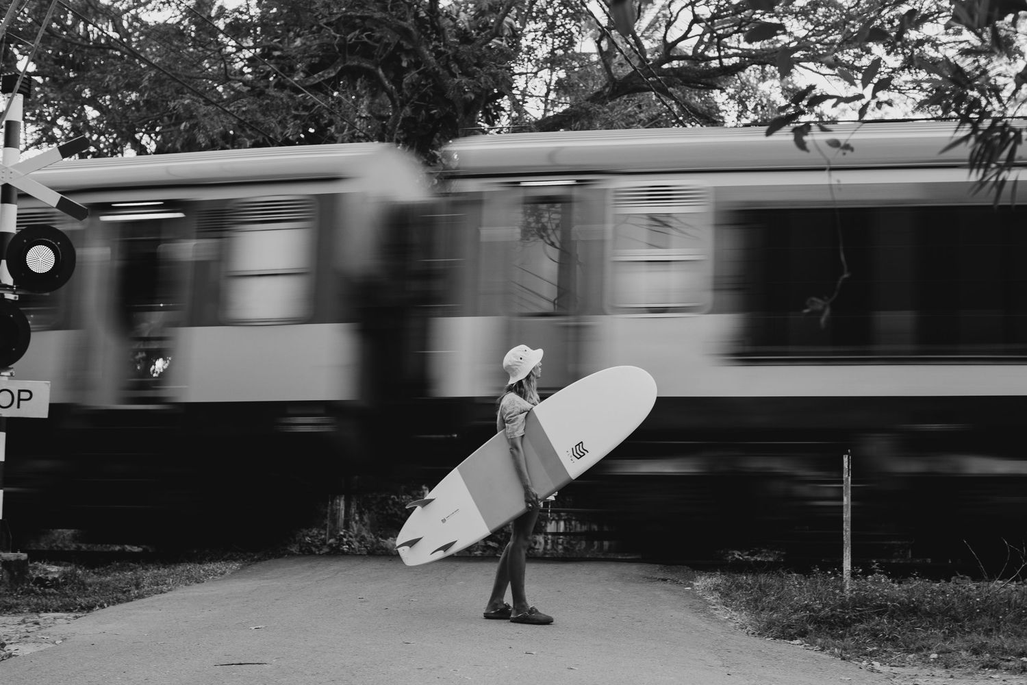 Motion blur of train passing by with surfer waiting at station platform.