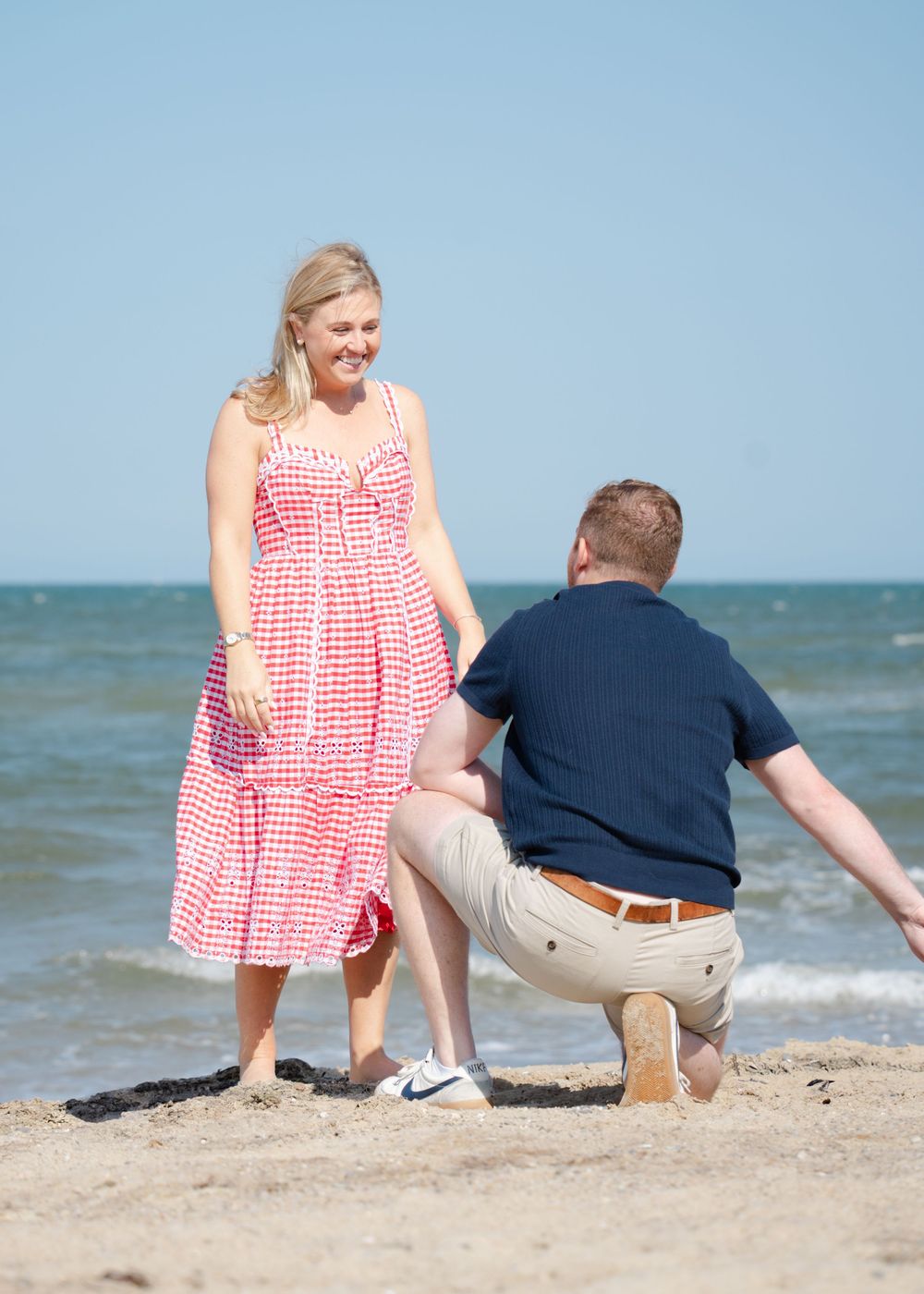 Emotional proposal moment, man down on one knee, on a beach in Cape Cod.