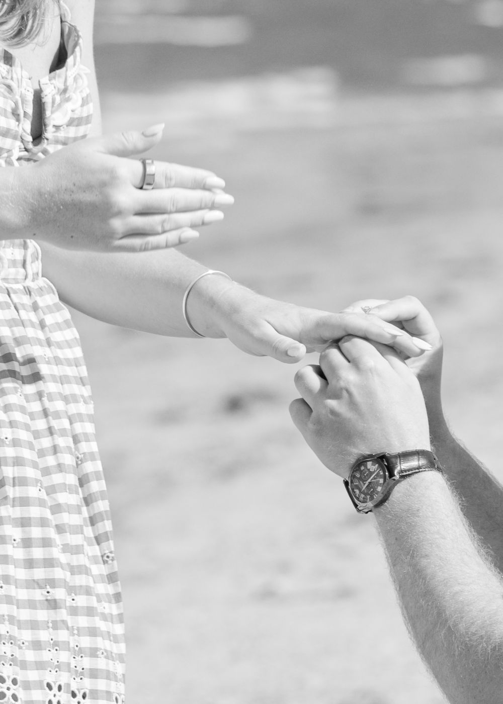 Close-up of engagement ring, ocean waves softly blurred in the background at Cape Cod beach.