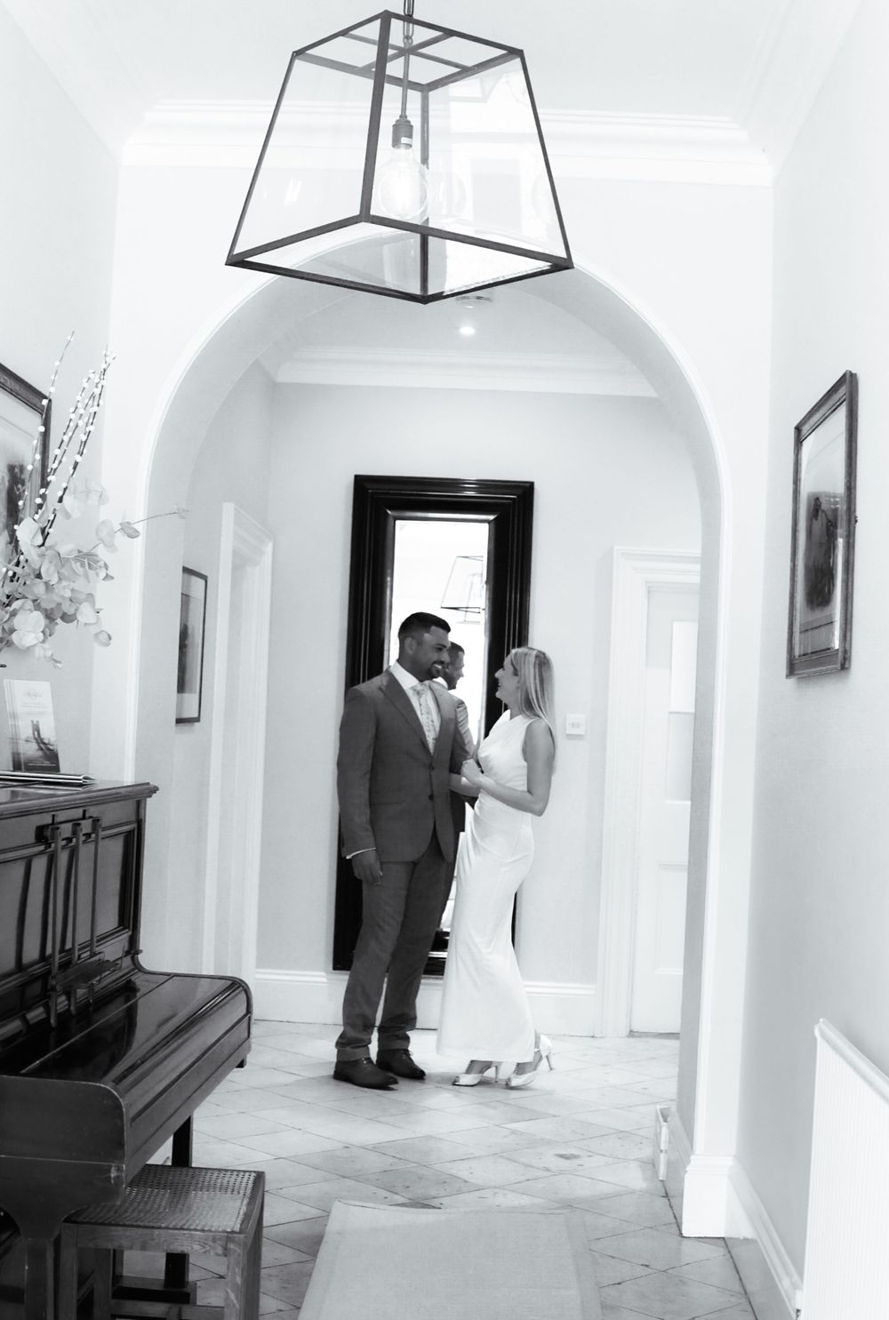 Timeless image, formal couple sharing quiet connection in sleek, modern hallway.