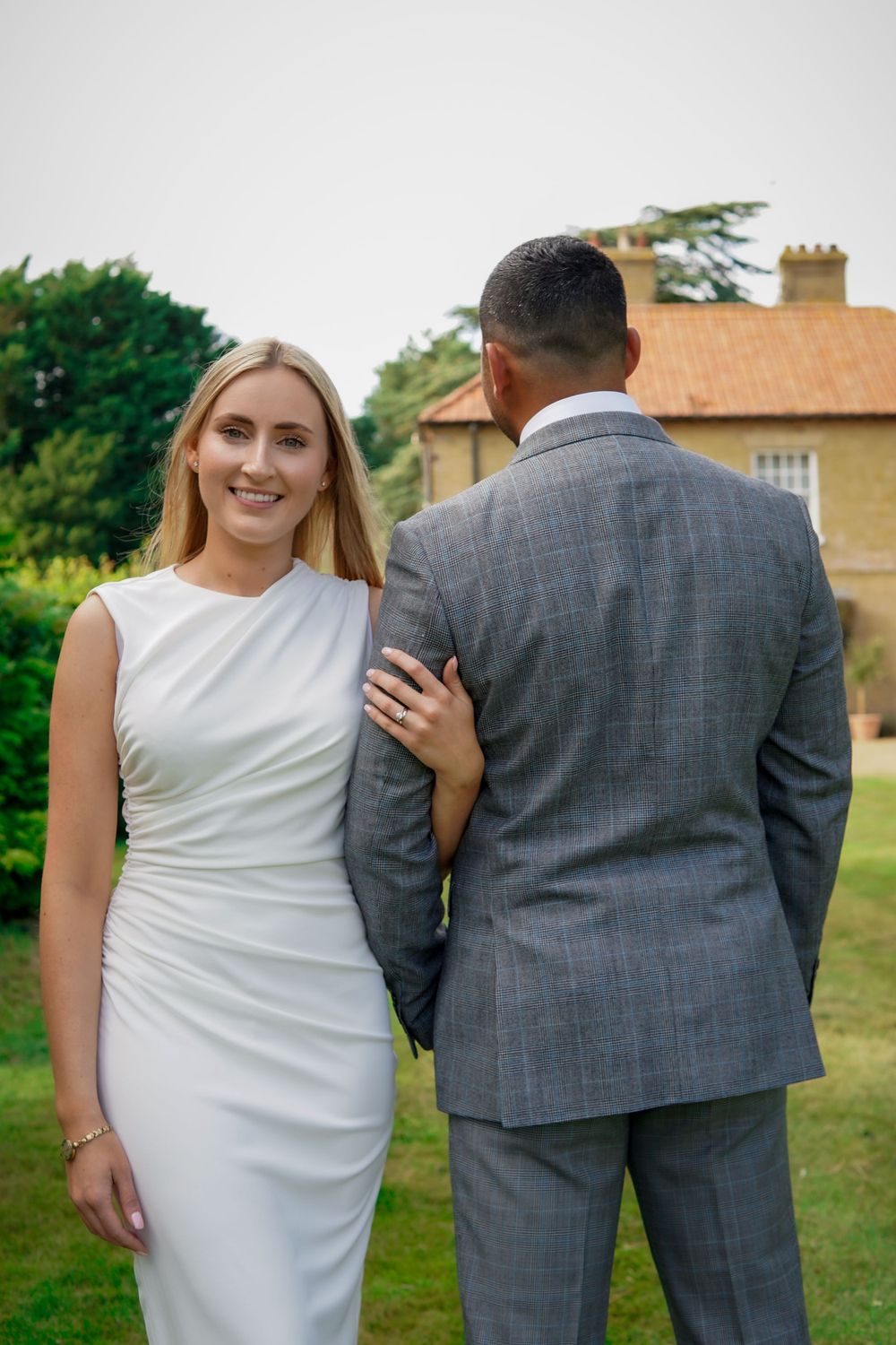 Romantic wedding portrait, bride and groom standing together in garden near historic home.
