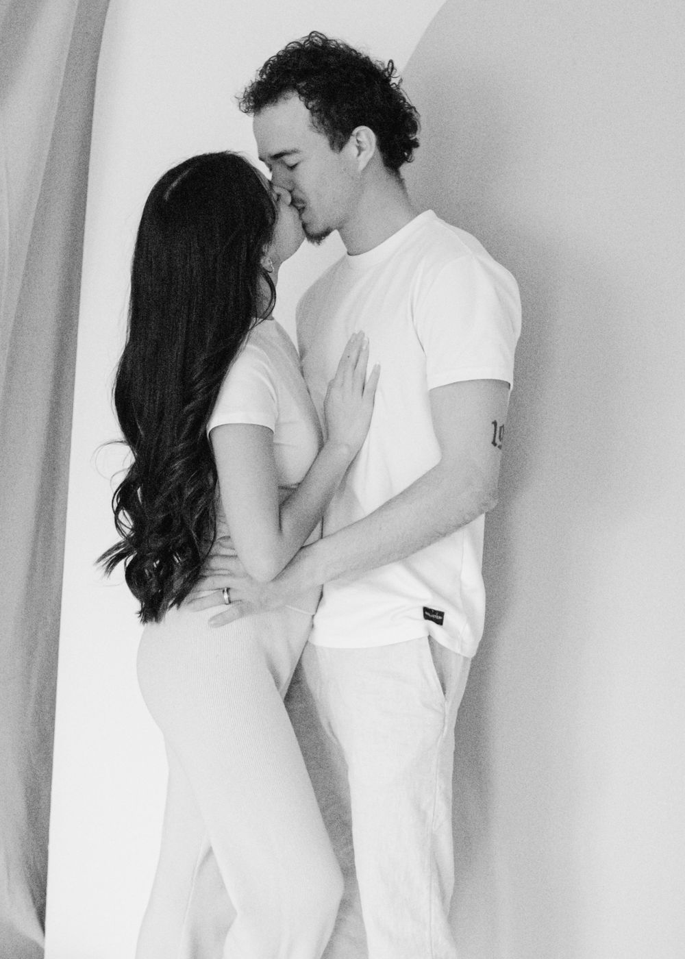 Candid black and white couples portrait, tender embrace and soft smiles
