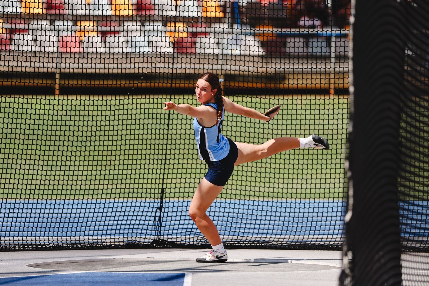 Athlete performing discus throw technique in stadium.