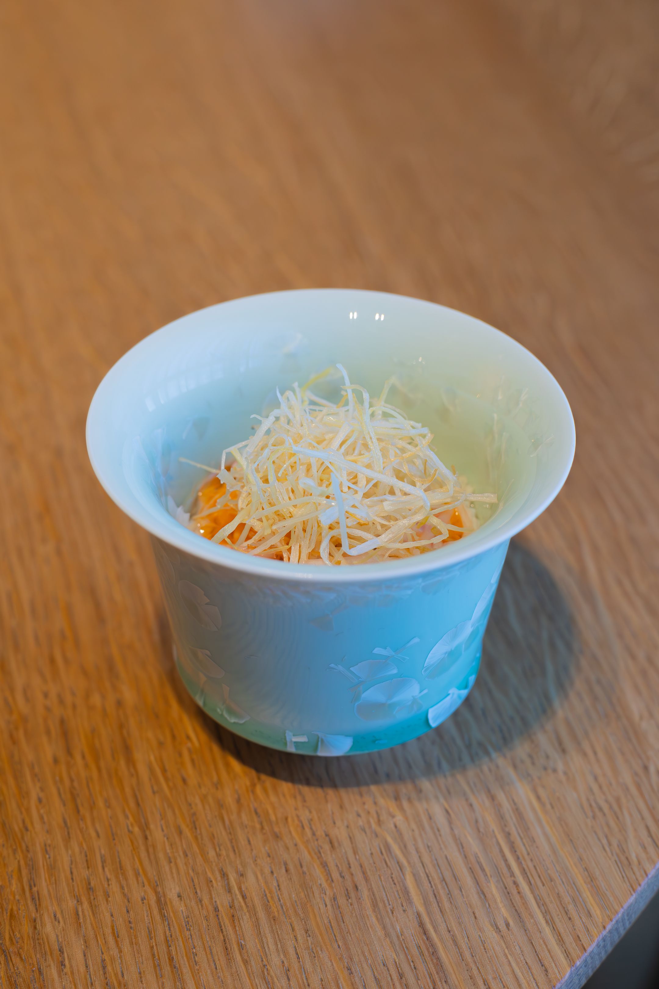 Light blue ceramic bowl filled with shredded daikon and carrot salad.