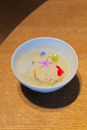 Delicate clear soup with floating colorful flower petals in an artistic presentation.