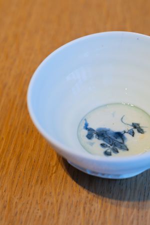 White ceramic bowl with decorative blue designs containing a milky liquid.