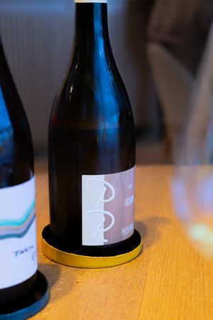 Dark wine bottle with minimalist white label and yellow coaster.