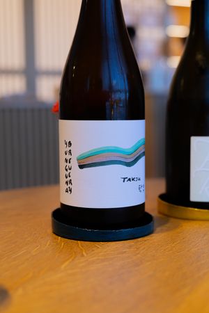 Wine bottle with abstract wavy design and numbers on label sitting on wooden surface.