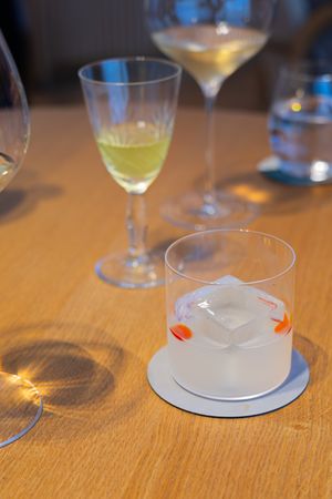 Various cocktail glasses with clear and colored drinks on wooden table.