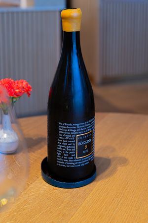 Dark wine bottle with text label and yellow wax seal on wooden table.