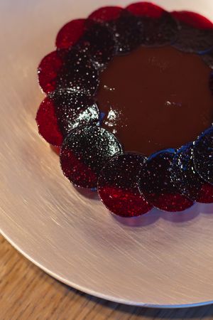 Close-up of chocolate tart decorated with overlapping berry slices in circular pattern.