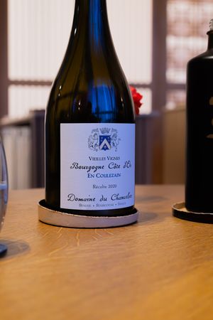 Bottle of Bourgogne Cote de Beaune wine with traditional label on wooden surface.