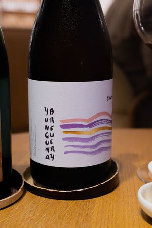 Wine bottle with minimalist label showing colorful wavy stripes in purple and orange tones.