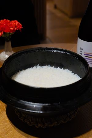 Black ceramic bowl filled with white salt or granules on wooden surface.
