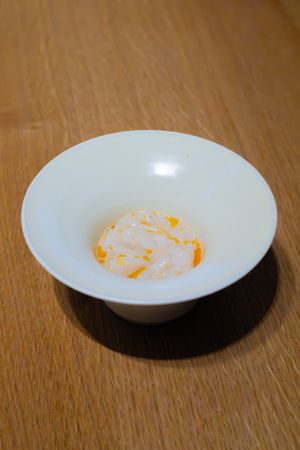 White ceramic bowl with orange-tinted sauce or reduction.