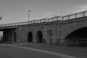 Stone bridge with arched openings photographed in black and white.