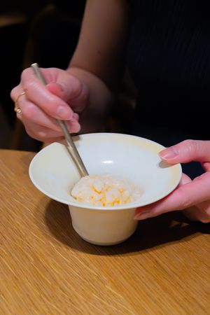 White ceramic bowl being eaten from with spoon on wooden table.