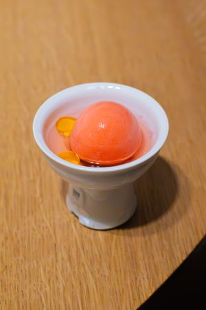 Orange sorbet with citrus segments in a white ceramic serving dish.