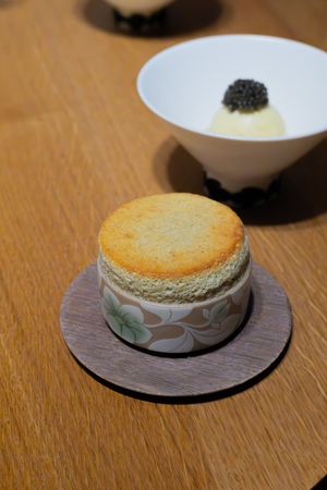 Elegant dessert presentation with caviar topping and a soufflé on wooden surface.