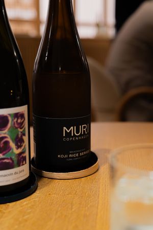 Wine bottle labeled Muri Copenhagen on wooden table surface.