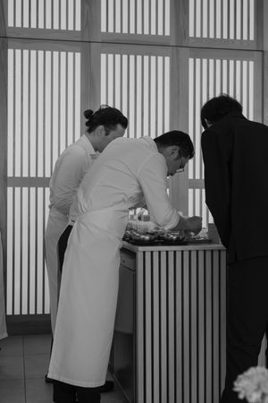 Kitchen staff working at a counter with geometric patterned wall panels.
