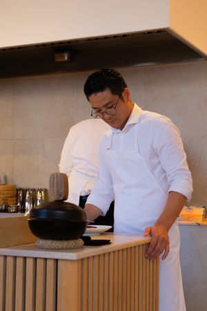 Chef in white uniform cooking at a modern kitchen counter.