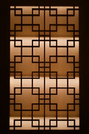 Geometric lattice pattern window screen with backlit warm lighting creating an elegant oriental design.