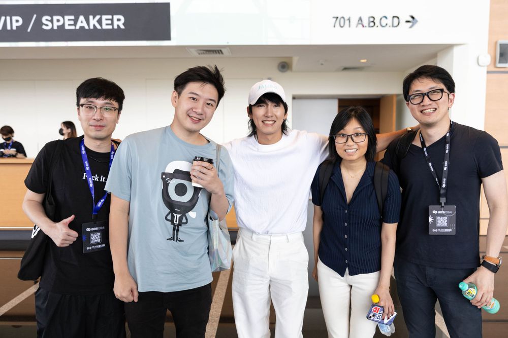 Group of five people smiling together near VIP speaker area at event.