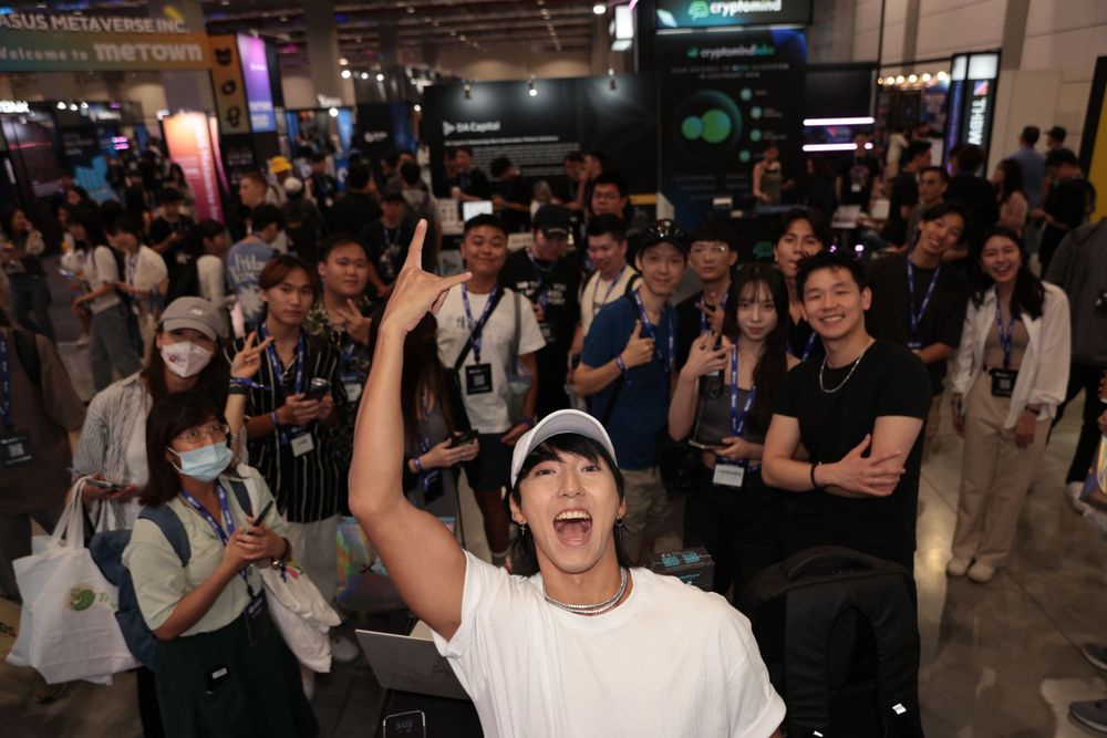 Excited man in white cap cheers with crowd at a tech expo event.