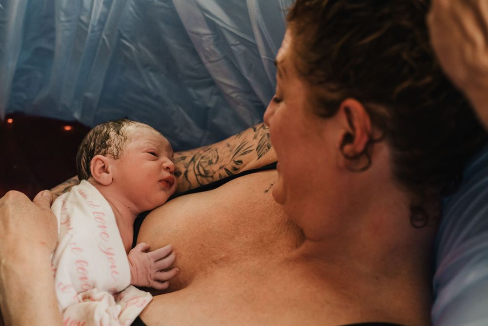 mom looks lovingly at her newborn after home water birth Lake Tahoe birth photography