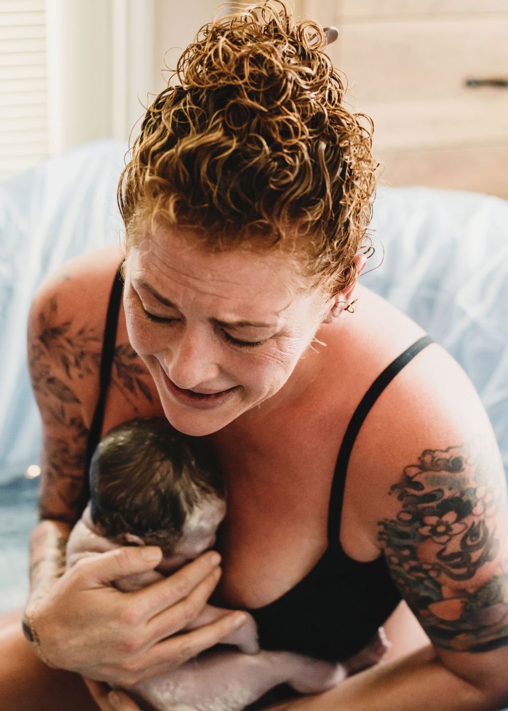 Mother catches and cradles newborn in birthing pool during home birth in Carson Valley